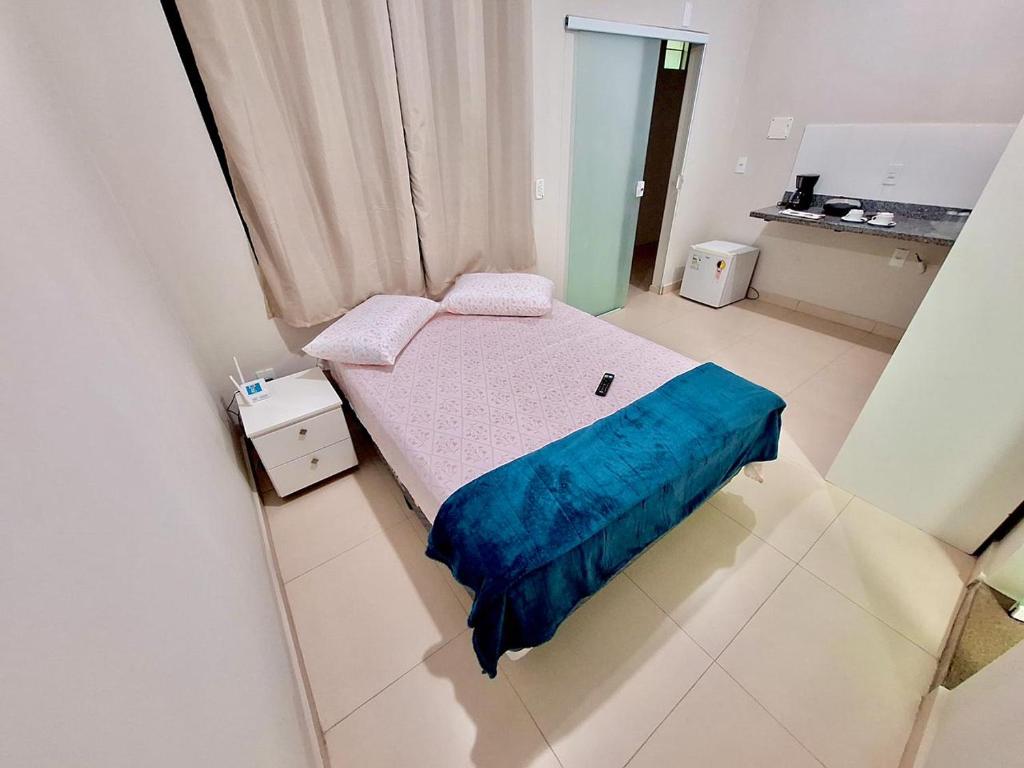 um pequeno quarto com uma cama com um cobertor azul em Studio #3 Rubi em Campos dos Goytacazes