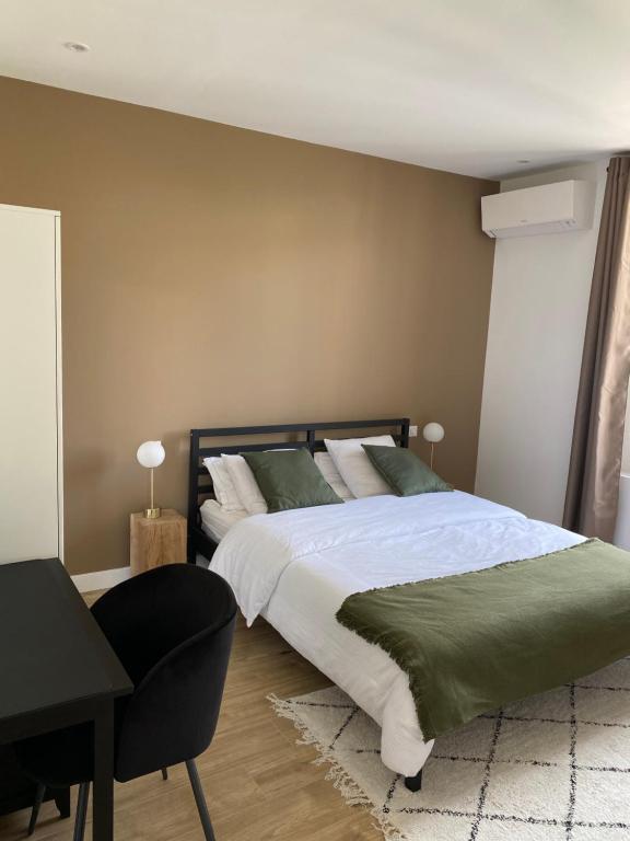 a bedroom with a bed with a desk and a chair at Appartement La Maouin 2 pièces in Saint-Laurent-du-Var