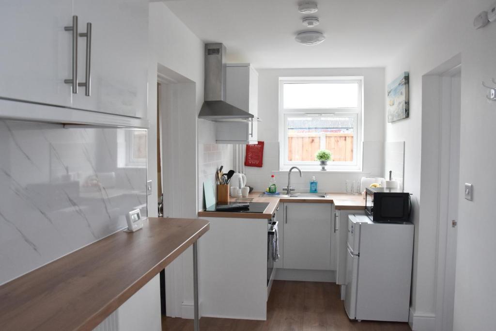 een keuken met witte kasten, een gootsteen en een raam bij Parkside Apartment in Norwich