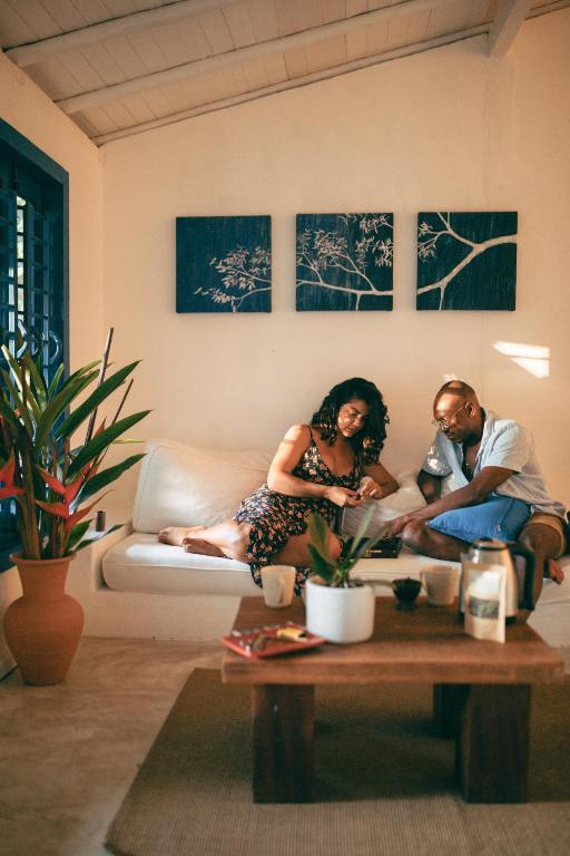 un hombre y una mujer sentados en un sofá en una sala de estar en Pousada Lagoa, en Caraíva
