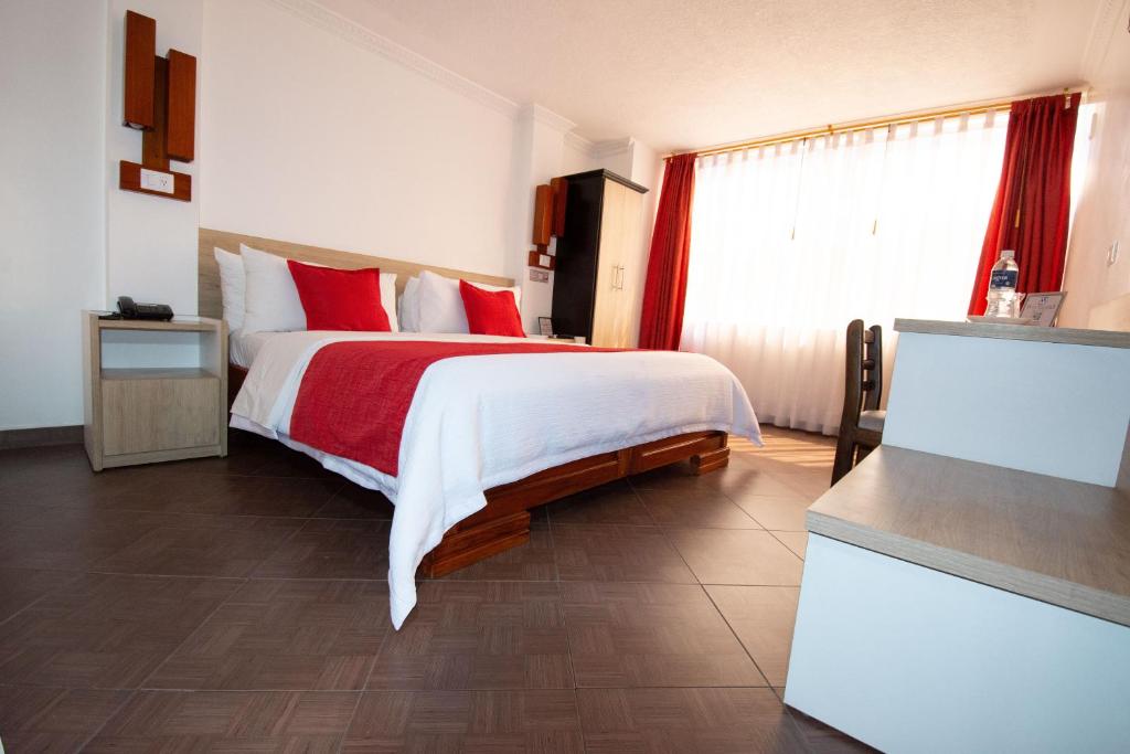 a bedroom with a large bed with red pillows at Hotel Plaza Victoria in Ibarra