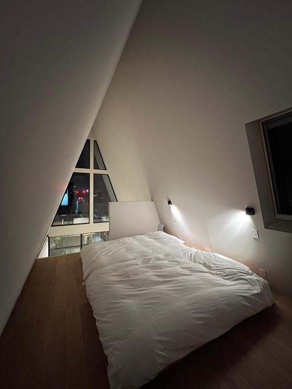 甲府的住宿－TRIGON HOUSE HOTEL KOFU，窗户客房内的一张白色床