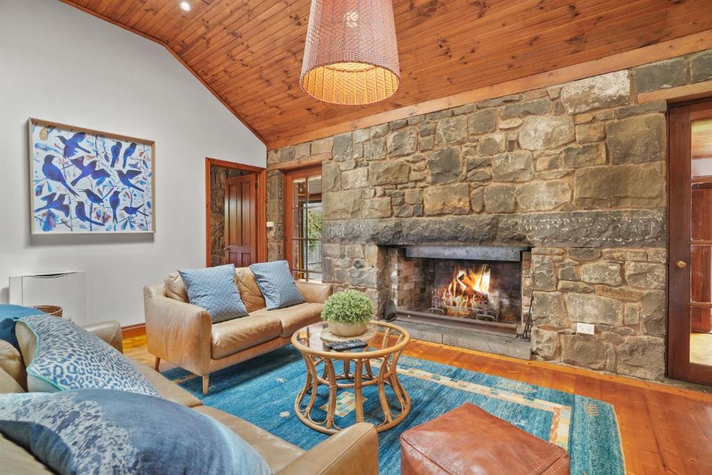 a living room with a stone fireplace at Breakfast Creek Cottage in Port Fairy