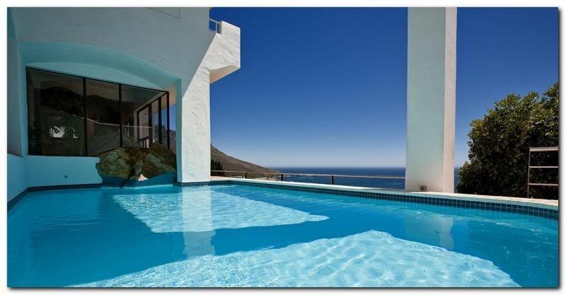 a large swimming pool with a view of the ocean at Bayview Penthouses and Rooms in Cape Town