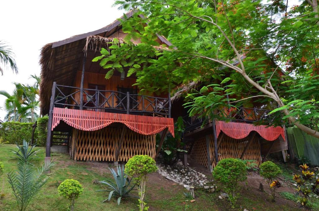 um edifício de madeira com varanda e árvores em Thongbay Guesthouse em Luang Prabang