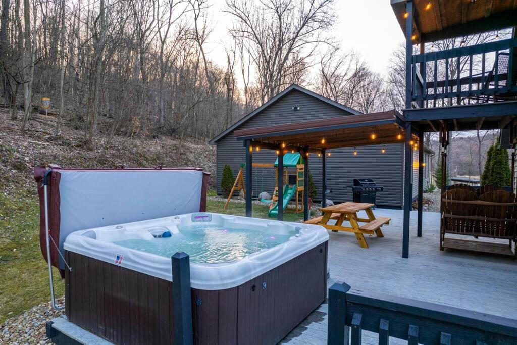 uma grande banheira de hidromassagem sentada num pátio com uma casa em Shady Point Retreat em Glenmont