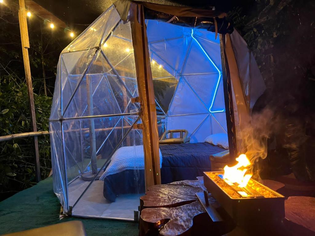 a bed in a dome tent with a fire at Mirador de la Montaña Glamping in San Francisco