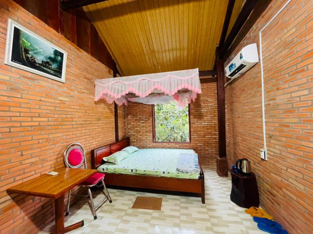 een slaapkamer met een bed, een tafel en een raam bij Forest Side Ecolodge in Cat Tien