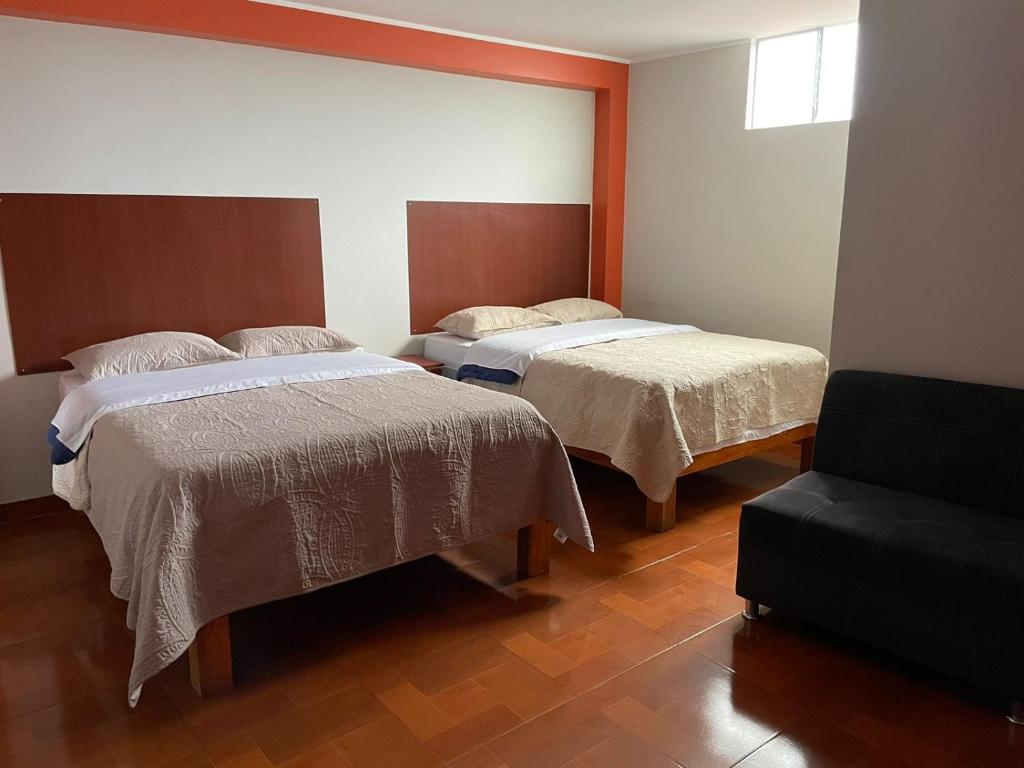 una camera con due letti e una sedia di CASA HOSPEDAJE LAS MONTAÑAS a Huancayo