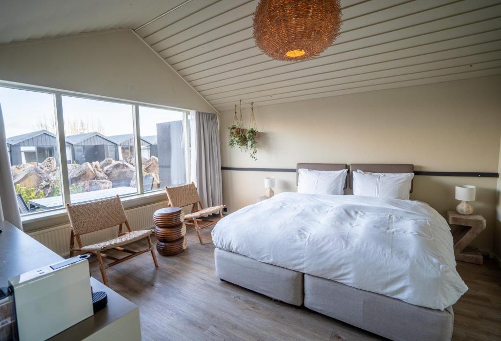 a bedroom with a white bed and a large window at The Hill Hotel at Flúðir in Fludir