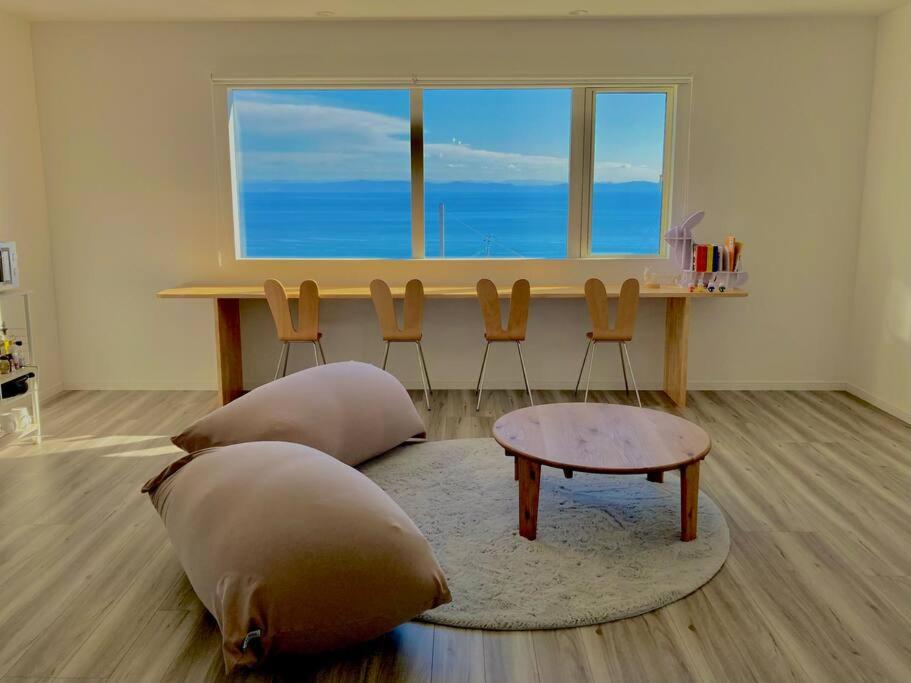 a living room with a table and two pillows at 「淡路島一棟貸宿　野うさぎ 」高台から海を望む貸別荘！2023年新築離れの素泊まり in Noda