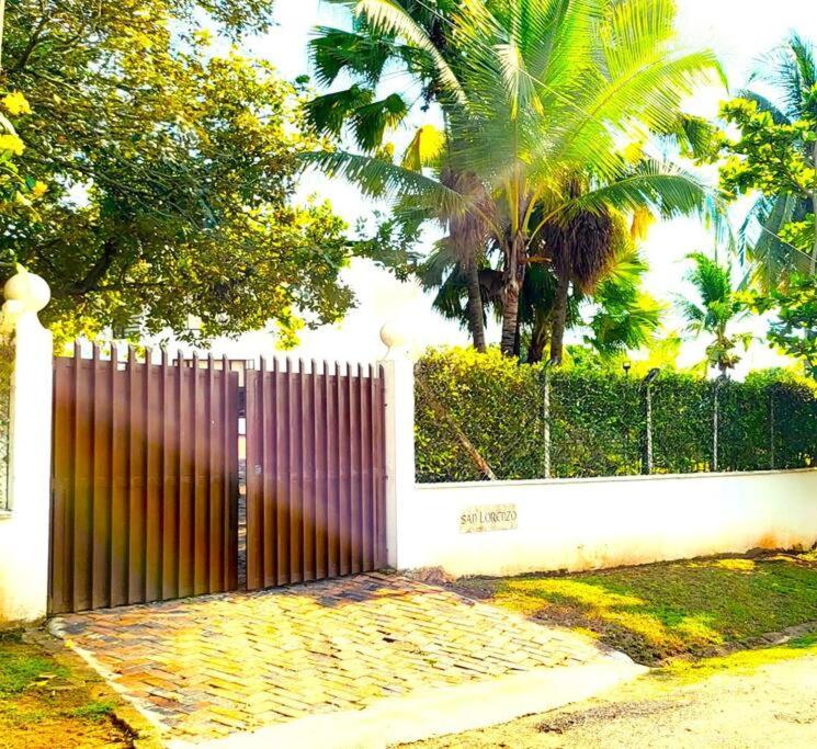 a fence with a purple gate and palm trees at Espectacular CASA FINCA con piscina, WiFi Y AA in Melgar