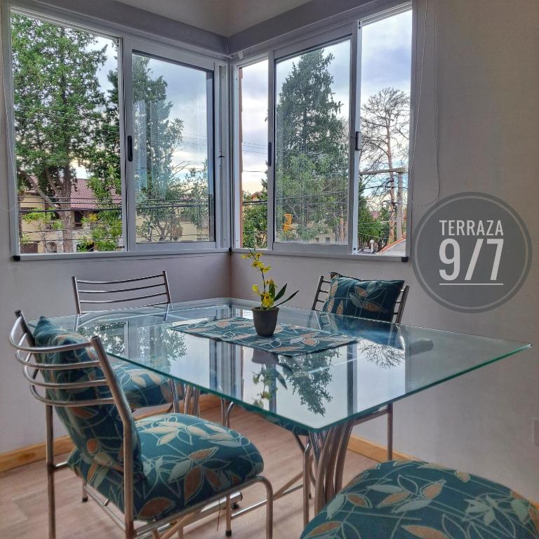 een glazen tafel en stoelen in een kamer met ramen bij Loft Terraza 9I7 Cochera en Excelente Ubicación in Villa Mercedes