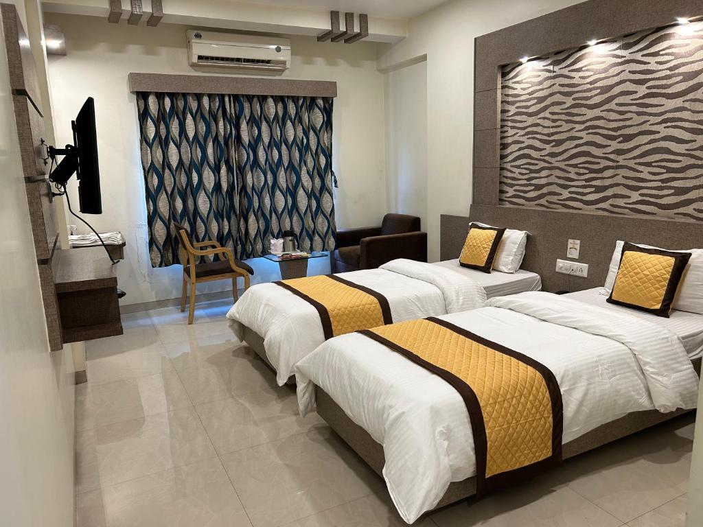 a hotel room with two beds and a television at Hotel Orange in Vapi