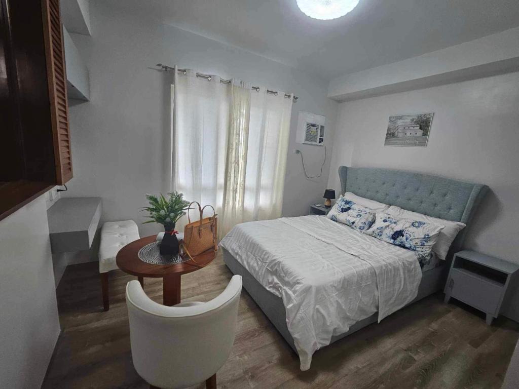 een slaapkamer met een bed, een tafel en een stoel bij Drew Pawns condo in Bacolod