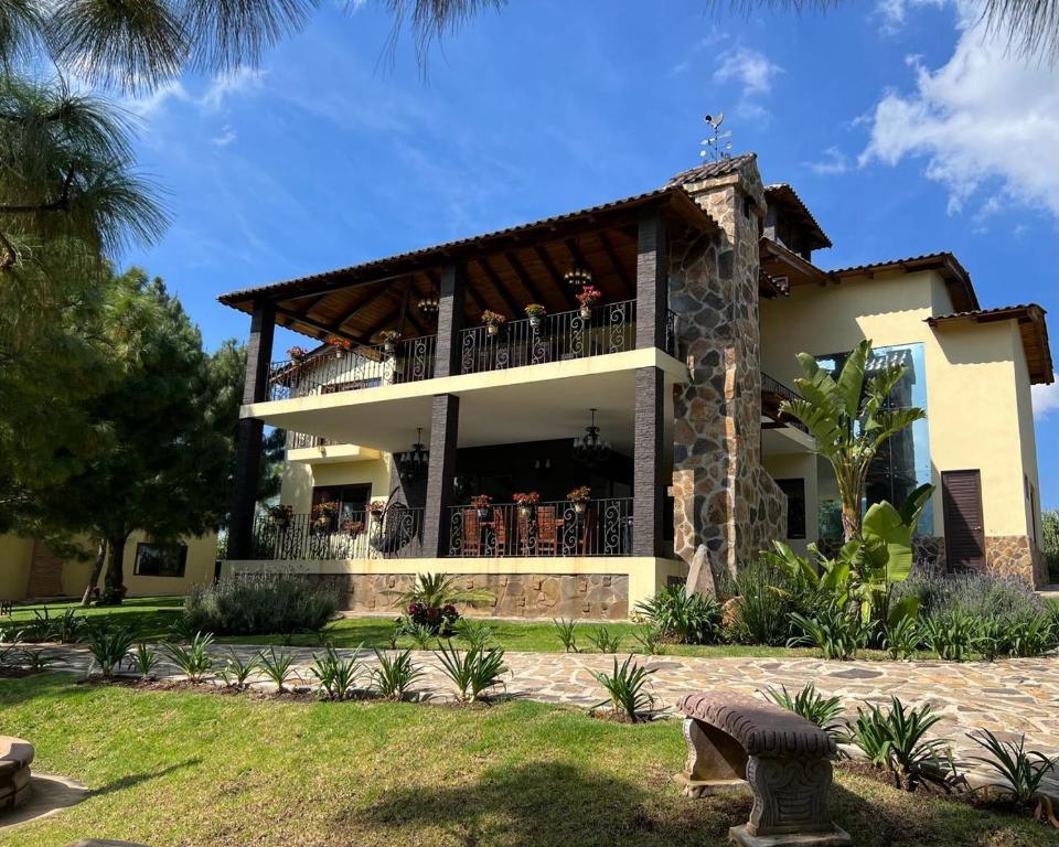 a house with a balcony with people on it at Cabaña No. 5 Puerta del Bosque Mazamitla. in Mazamitla