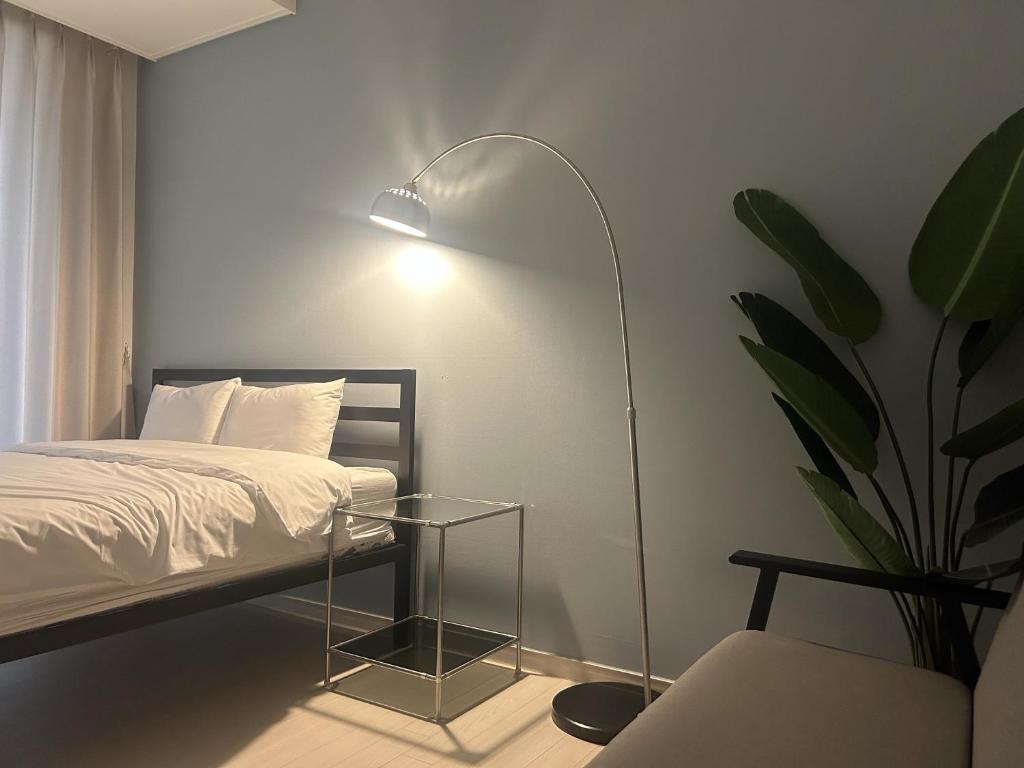 1 dormitorio con 1 cama con lámpara y planta en Landmark Songdo Stay, en Incheon