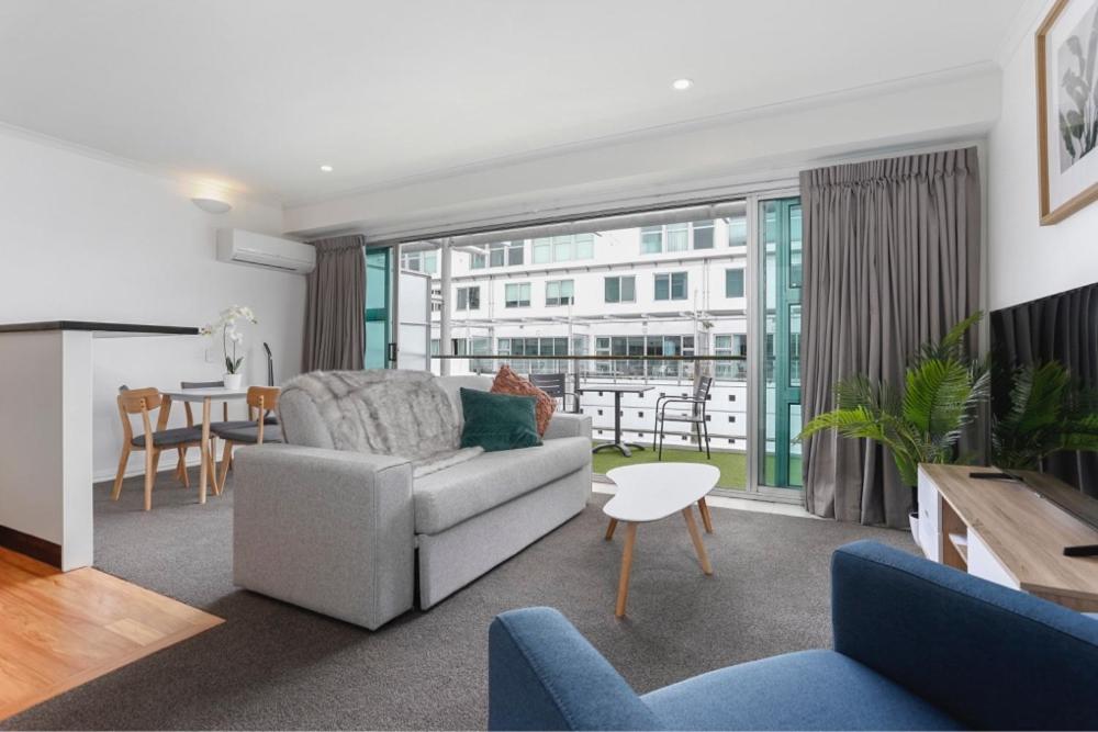 een woonkamer met een bank en een tafel bij Welcome To Your Secluded Luxury Abode in Auckland