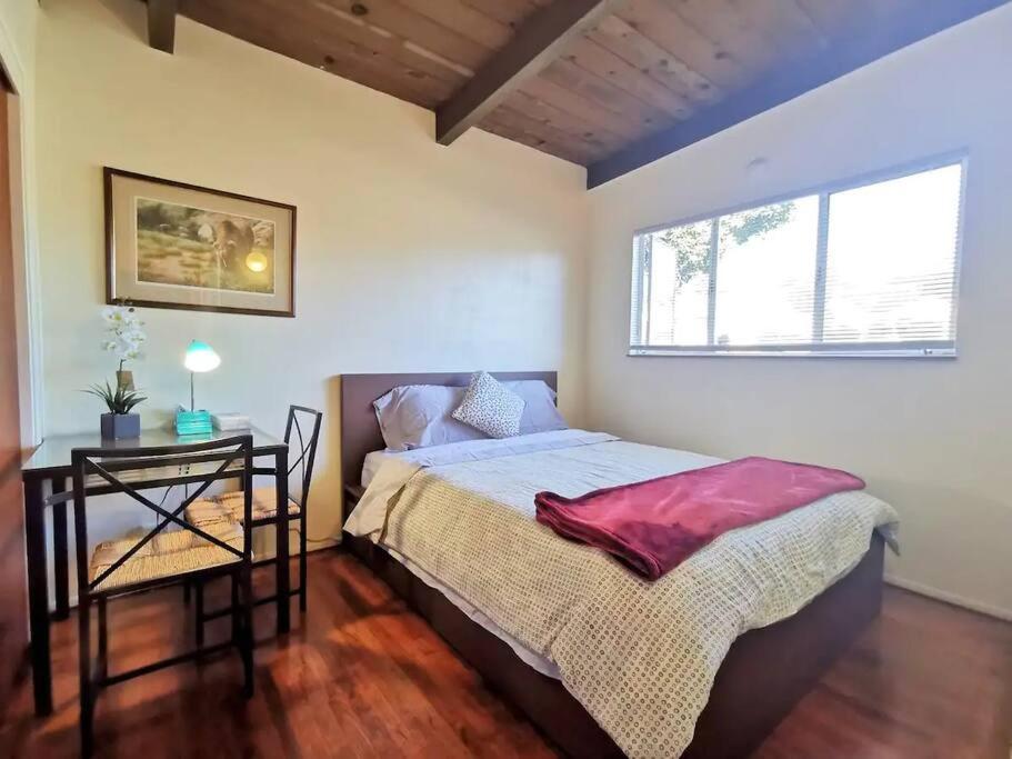Schlafzimmer mit einem Bett, einem Tisch und einem Fenster in der Unterkunft Cozy 2Br 1Bath Home w/ Parking near El Cerrito and University of Berkeley in Richmond