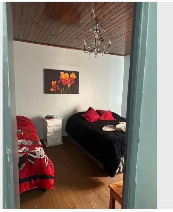 um quarto com uma cama preta e almofadas vermelhas em Parana house em Puerto Iguazú