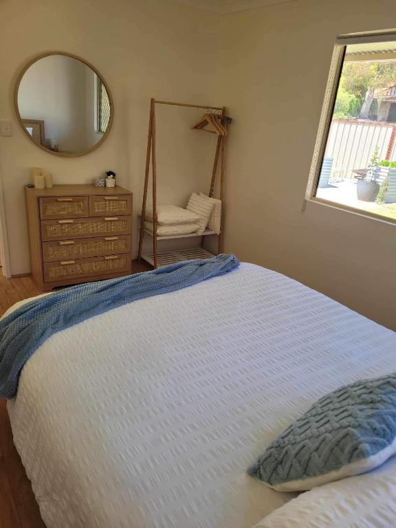 a bedroom with a bed with a mirror and a dresser at G&R Beach Cottage in Warnbro