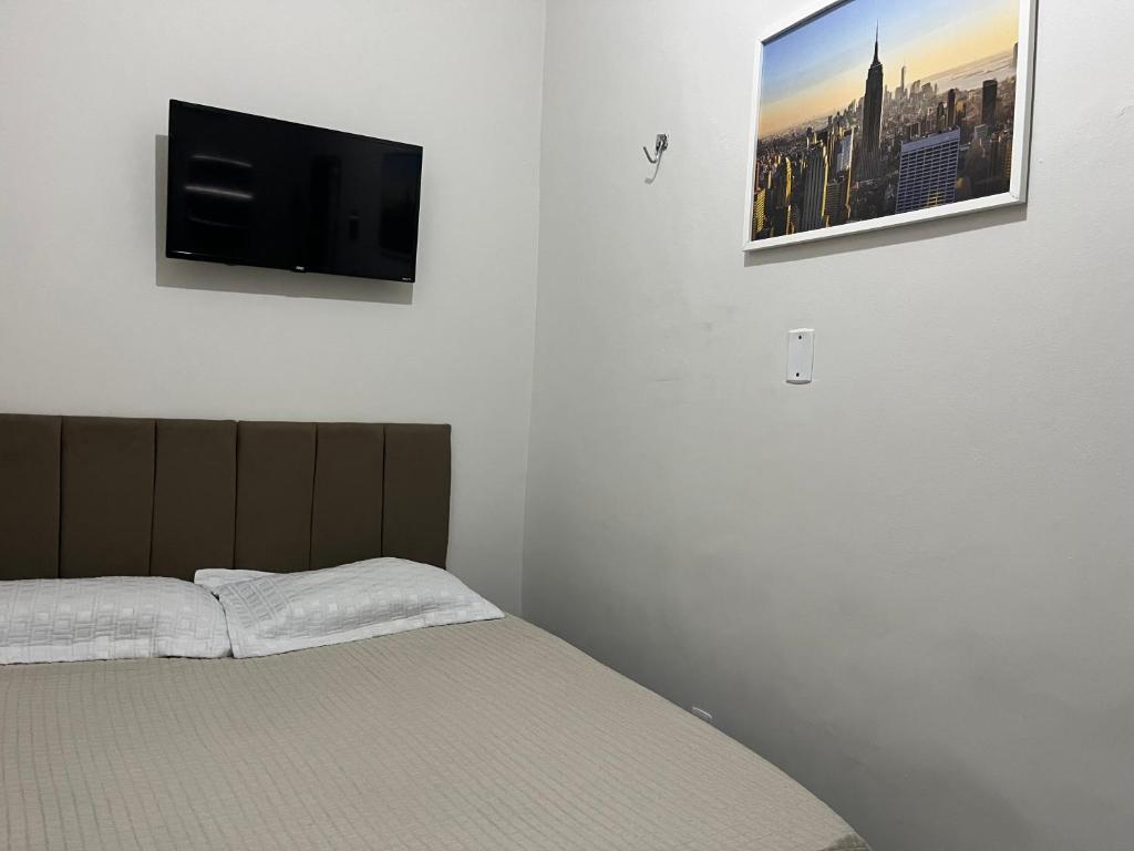Schlafzimmer mit einem Bett und einem Flachbild-TV an der Wand in der Unterkunft •Incrível suíte com: acesso totalmente individual! in João Pessoa