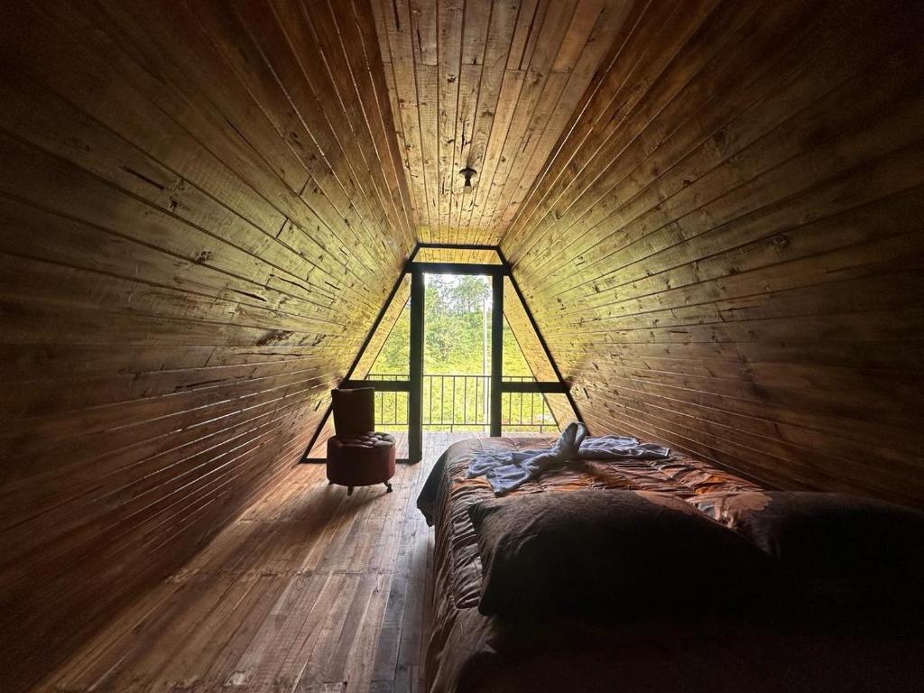 een kamer met een bed in een houten kamer met een raam bij Bungalow Tenorio Mountain Lodge in San Rafael