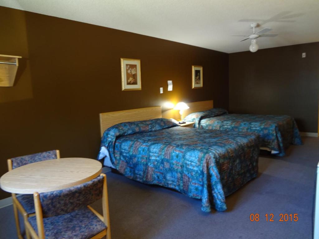 Habitación de hotel con 2 camas, mesa y sillas en Park Inn Motel en Kapuskasing