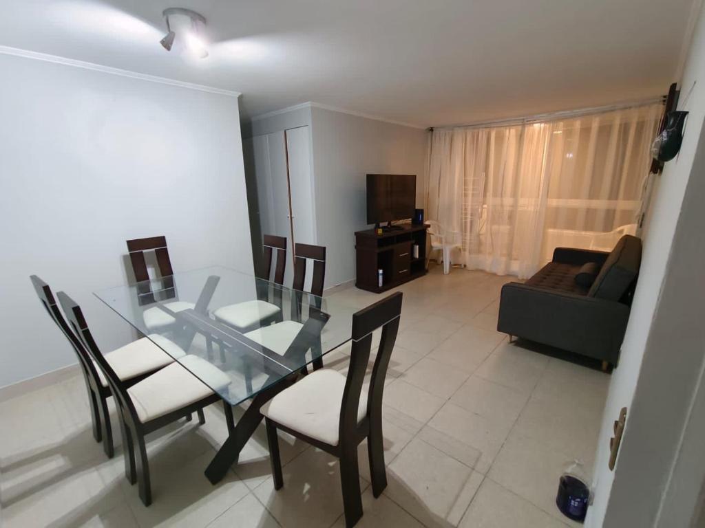 a dining room with a glass table and chairs at Departamento Condominio Arica in Arica