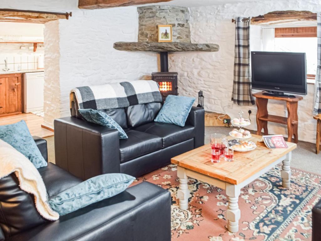 a living room with a leather couch and a table at Y Beudy - Uk46191 in Llanybydder