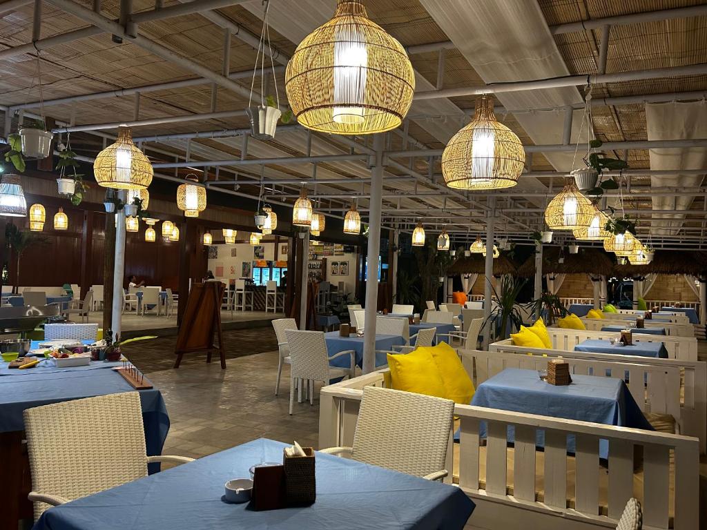 un restaurante con mesas azules, sillas y luces en Unzipp Bungalows Gili Air en Gili Air
