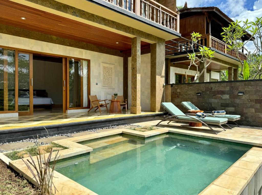 a swimming pool with two chairs and a house at Abian Ayu Villa in Sidemen