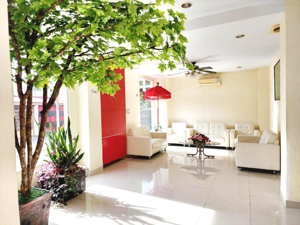 a living room with white furniture and a tree at HOTEL BALI MAKASSAR in Makassar