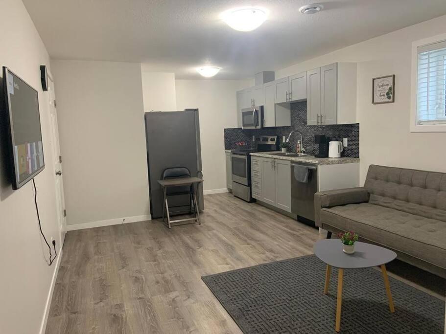 Una sala de estar con un sofá y una cocina. en Guest Suite with Queen Bed -Home Away from Home, en Regina