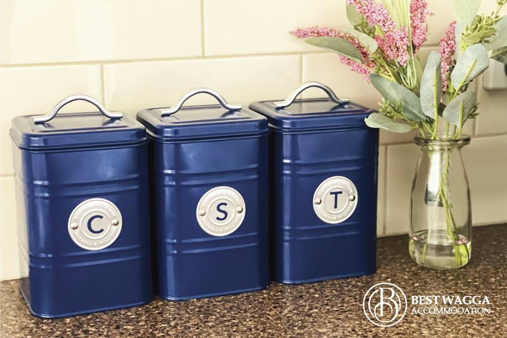 three blue trash cans sitting next to a vase with flowers at Suburban Bliss - Elegant Villa 1 in Wagga Wagga