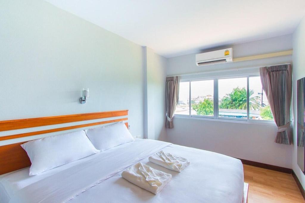 1 dormitorio con 1 cama blanca grande y ventana en PhetPhangan Hotel en Ban Tha Kup