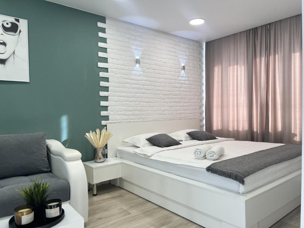 um quarto com uma cama branca e um sofá em Апартаменты с видом на город em Pavlodar