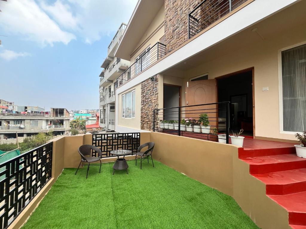 een balkon met 2 stoelen en een tafel en gras bij Mulberry Inn BnB in Shillong
