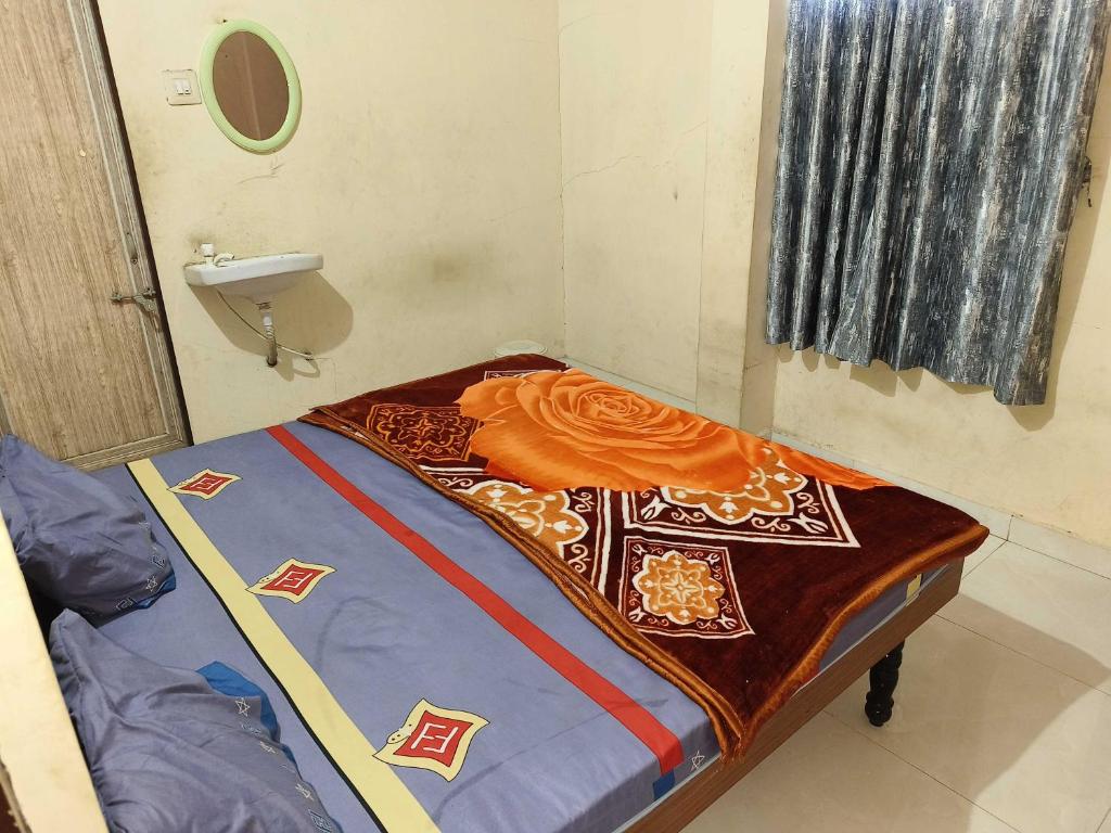 a small room with a bed with an orange blanket at SPOT ON Hotel VIP Inn in Jamnagar