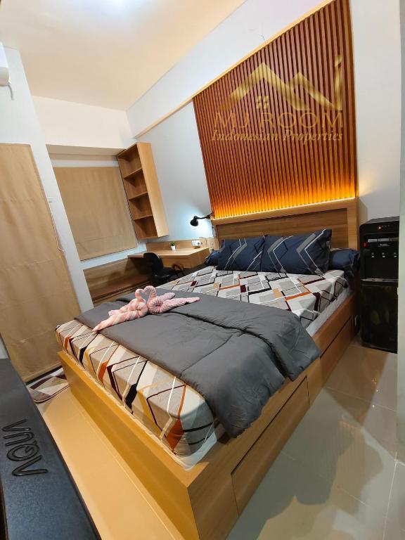 Schlafzimmer mit einem großen Bett mit einem Kopfteil aus Holz in der Unterkunft Trans Park Juanda Bekasi By MJ Room in Padurenan