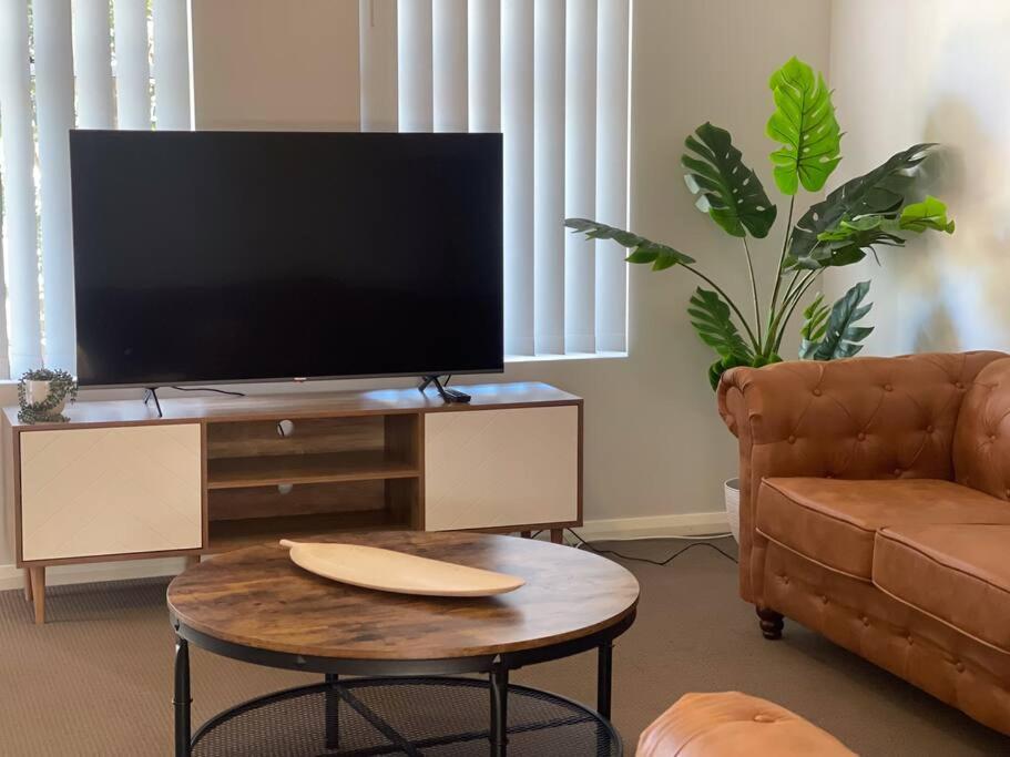 sala de estar con TV y mesa de centro en Serene Wagga Townhouse Getaway, en Wagga Wagga