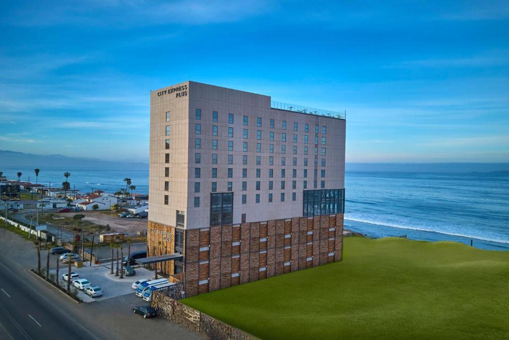 Un hôtel avec l'océan en arrière-plan dans l'établissement City Express Plus by Marriott Ensenada, à Ensenada