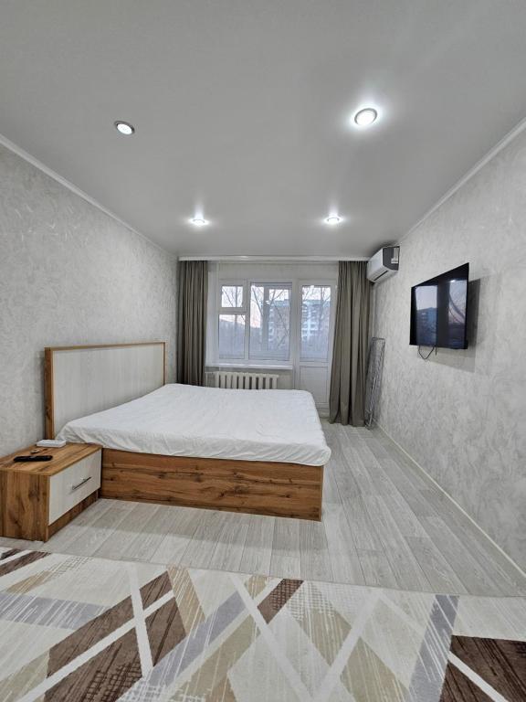 um quarto com uma cama e uma televisão de ecrã plano em 1 ком квартира ТД Астана em Oral