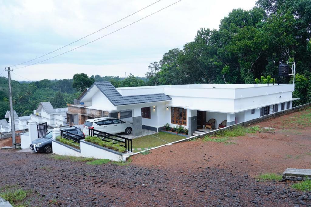 ein weißes Haus mit davor geparkt in der Unterkunft Woodland Escape Villas by Lexstays in Ettumānūr
