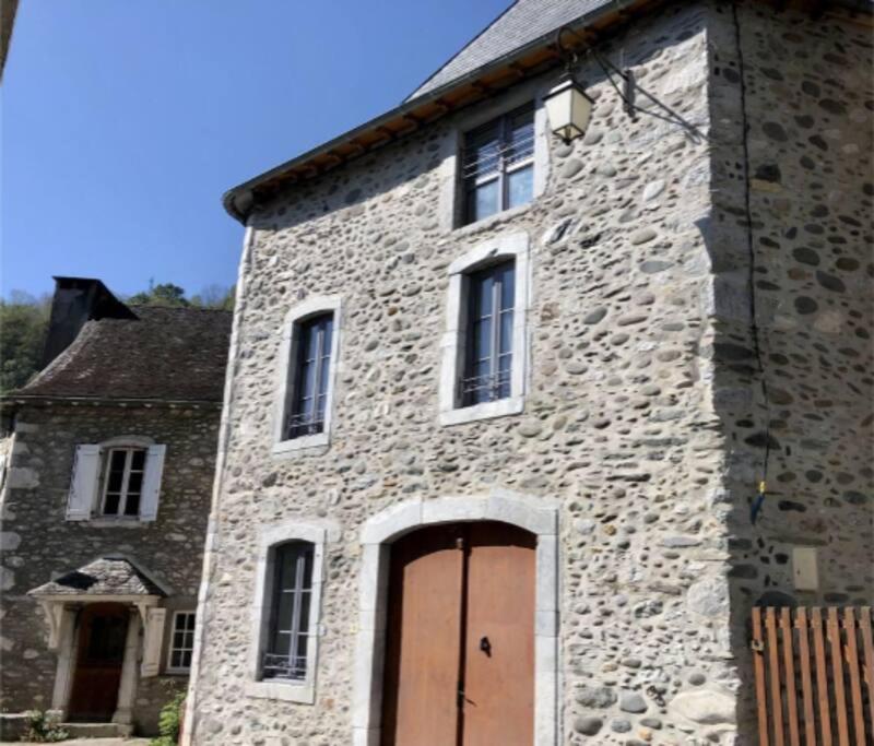 - un vieux bâtiment en pierre avec une porte marron dans l'établissement Maison de montagne, à Sarrance