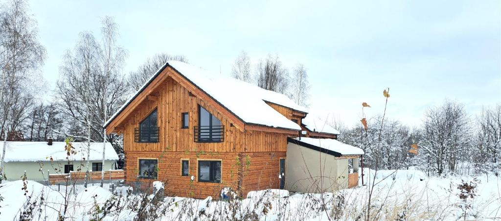 una casa in legno con neve sul tetto di wellness roubenka Holčí a Miřetice
