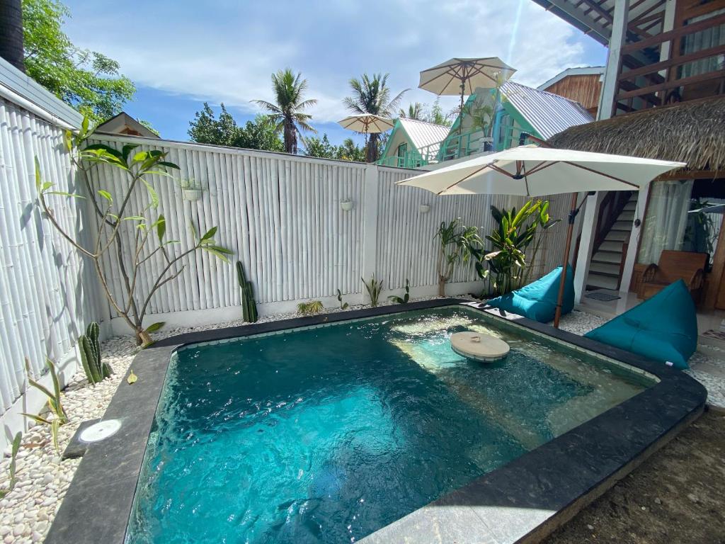 a small swimming pool with an umbrella and anophe at Rascal House Gili Trawangan in Gili Trawangan