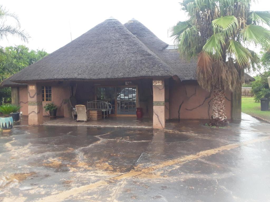 uma casa com um telhado de palha com uma palmeira em Loding Lodge em Loding
