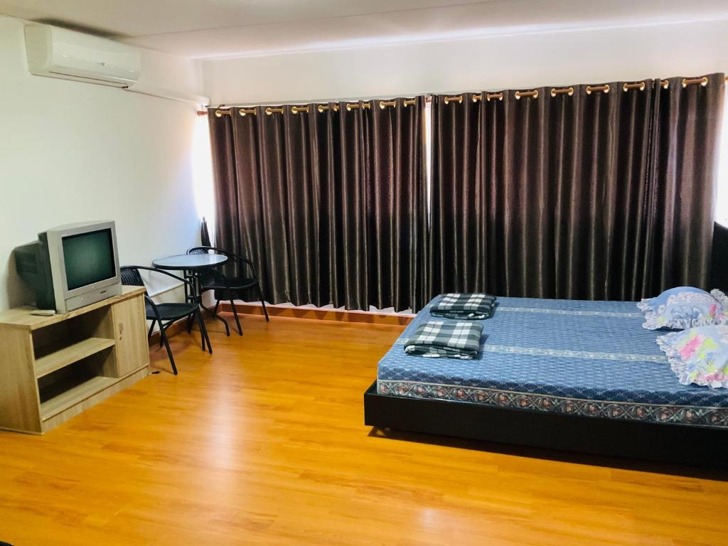 a bedroom with a bed and a television and a table at Muangthong T4,T5near Impact,Challenger in Nonthaburi