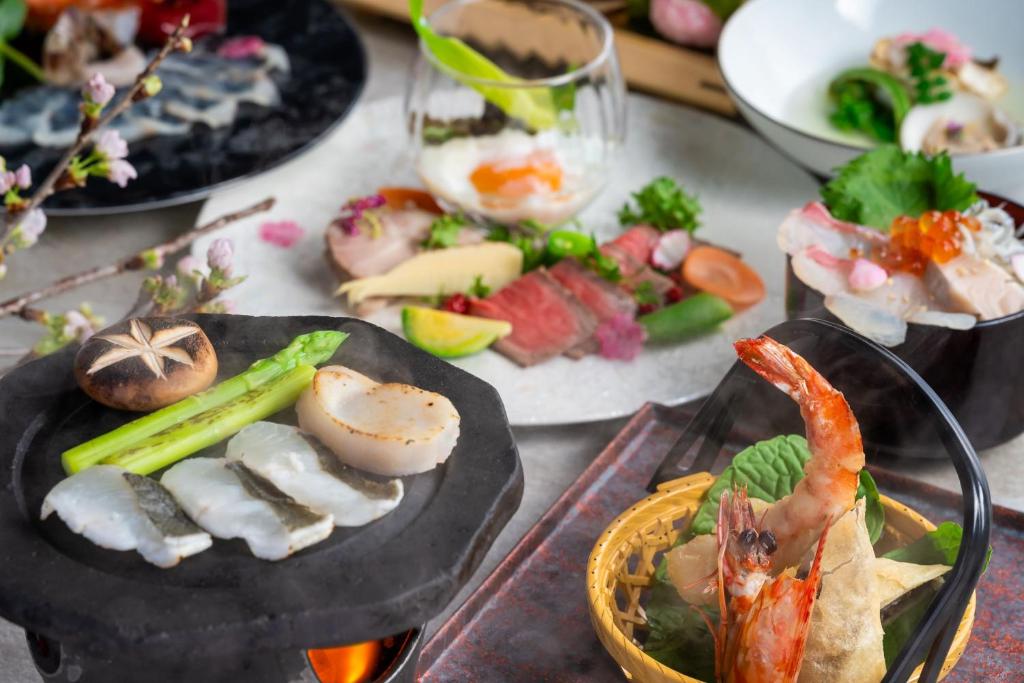 a table topped with plates of food with seafood and vegetables at KAMENOI HOTEL Setouchi Hikari in Hikari